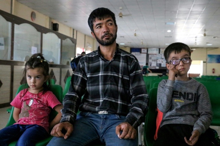 An Afghan refugee sits with his children after their deportation from Iran, at a registration centre near the Afghanistan-Iran border in the Islam Qala district of Herat province