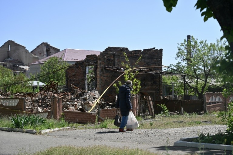 A local resident walks past a destroyed house in the town of Lyman, near the frontline in the Donetsk region in Ukraine