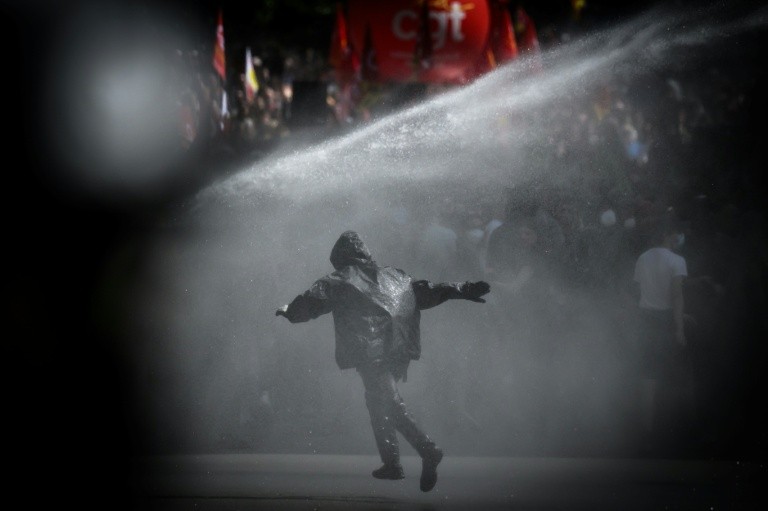 A protester is sprayed with water from a water cannon during a May Day rally in Nantes