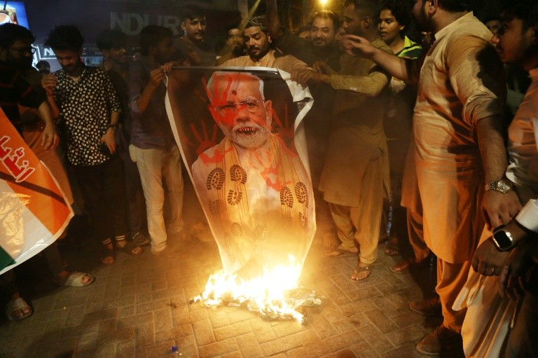 Demonstrators burn a banner with a picture of India's Prime Minister Narendra Modi during an anti-India protest in Hyberabad, Sindh province