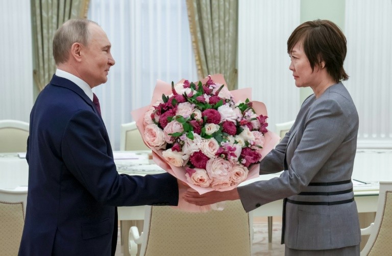 In this pool picture distributed by the Russian state agency Sputnik, Russia's President Vladimir Putin gives a bunch of flowers to Akie Abe, widow of former Japanese premier Shinzo Abe, at the Kremlin