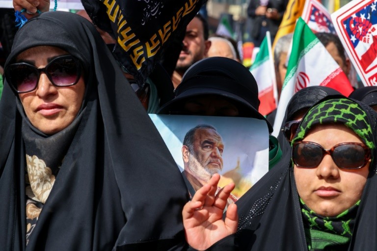 A woman holds a portrait of slain Iranian Revolutionary Guards commander Hossein Salami as mourners attend his funeral and that of other military commanders killed during Israeli strikes