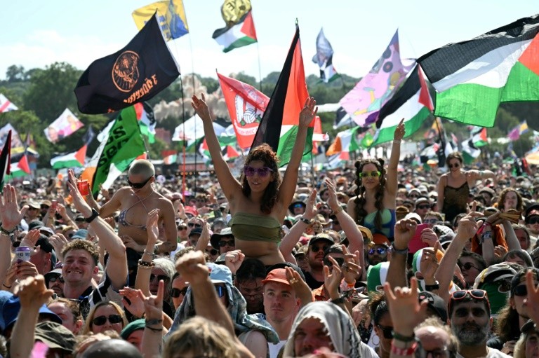 Thousands of festival-goers, many waving Palestinian flags, cheered Kneecap
