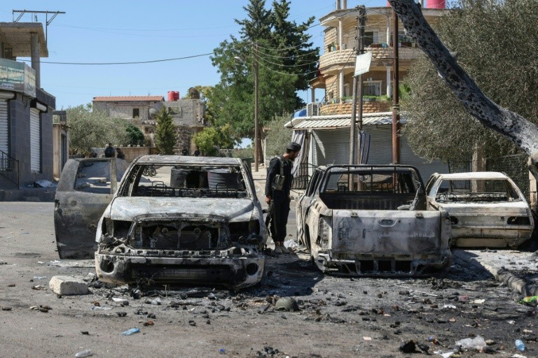 Torched vehicles lie abandoned in the streets of Sweida.