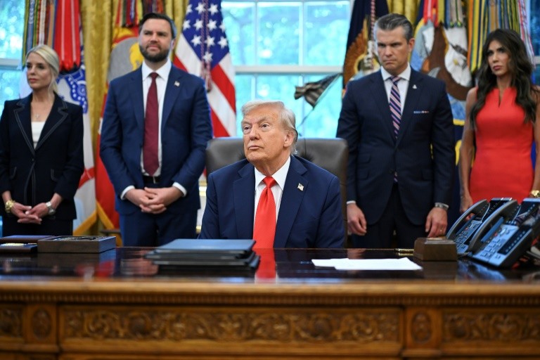 US President Donald Trump speaks to the press in the Oval Office, surrounded by top aides