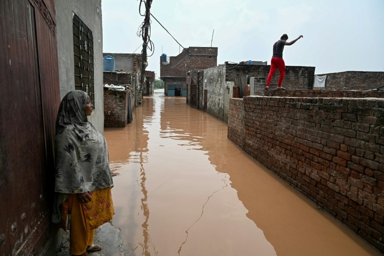 A woman stands near her submerged home, after floodwaters entered from the overflowing Ravi river in Shahdara, Lahore on August 29, 2025. Water has gushed into the eastern province, Pakistan's breadbasket and home to about half of its 255 million people,