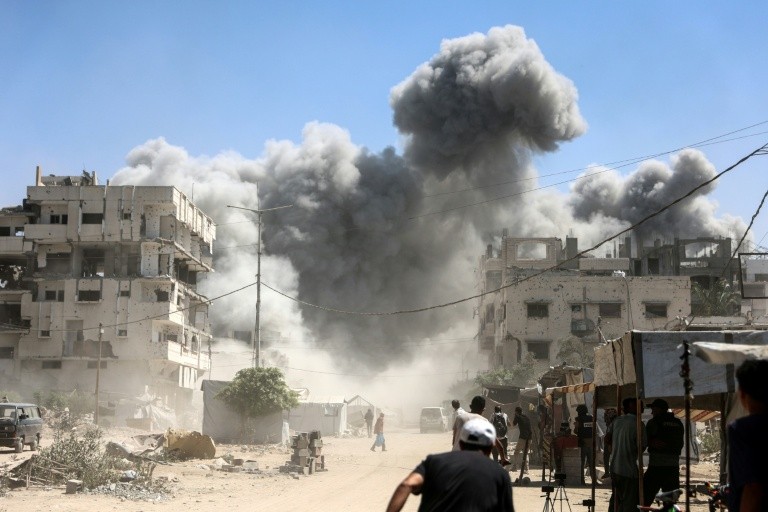 Palestinians watch as the Mhanna tower collapses amid heavy smoke, during an Israeli strike in the Tal el-Hawa neighbourhood of Gaza City on September 14, 2025